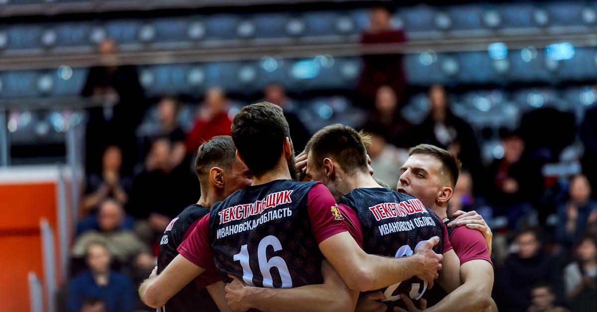 Volleyball players embrace in celebration during an indoor game.