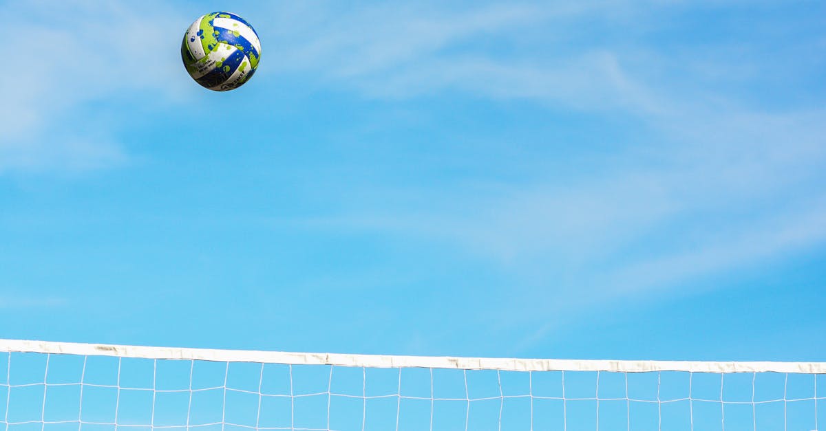 A vibrant volleyball against a clear blue sky over a net, capturing the essence of sports action and outdoor play.