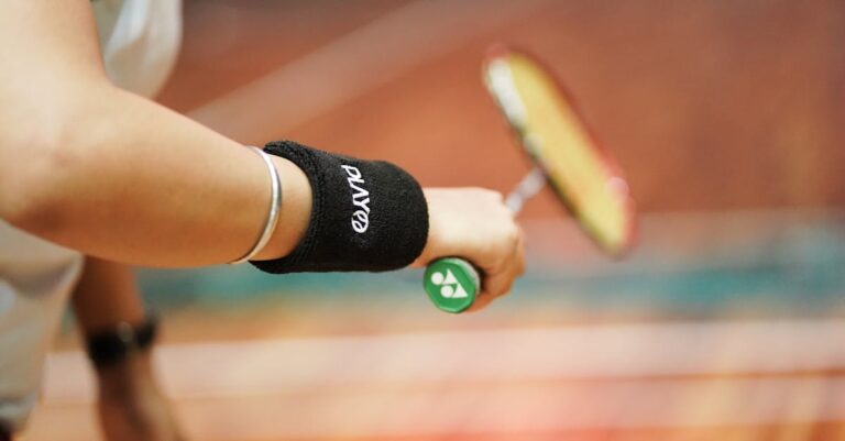 Focused close-up of a person's hand holding a badminton racket, highlighting action and precision in the sport.