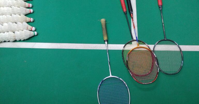 Top view of badminton rackets and shuttlecocks on an indoor court.