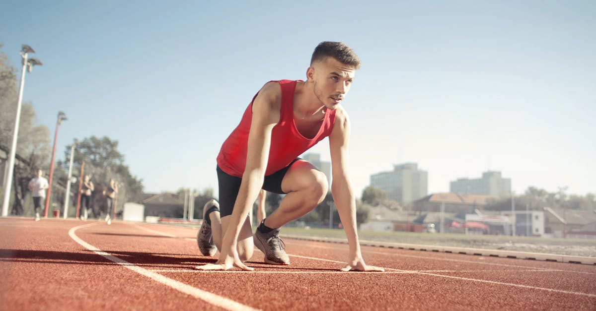 Young male athlete in start position on outdoor track, ready to sprint. teknik dasar lari