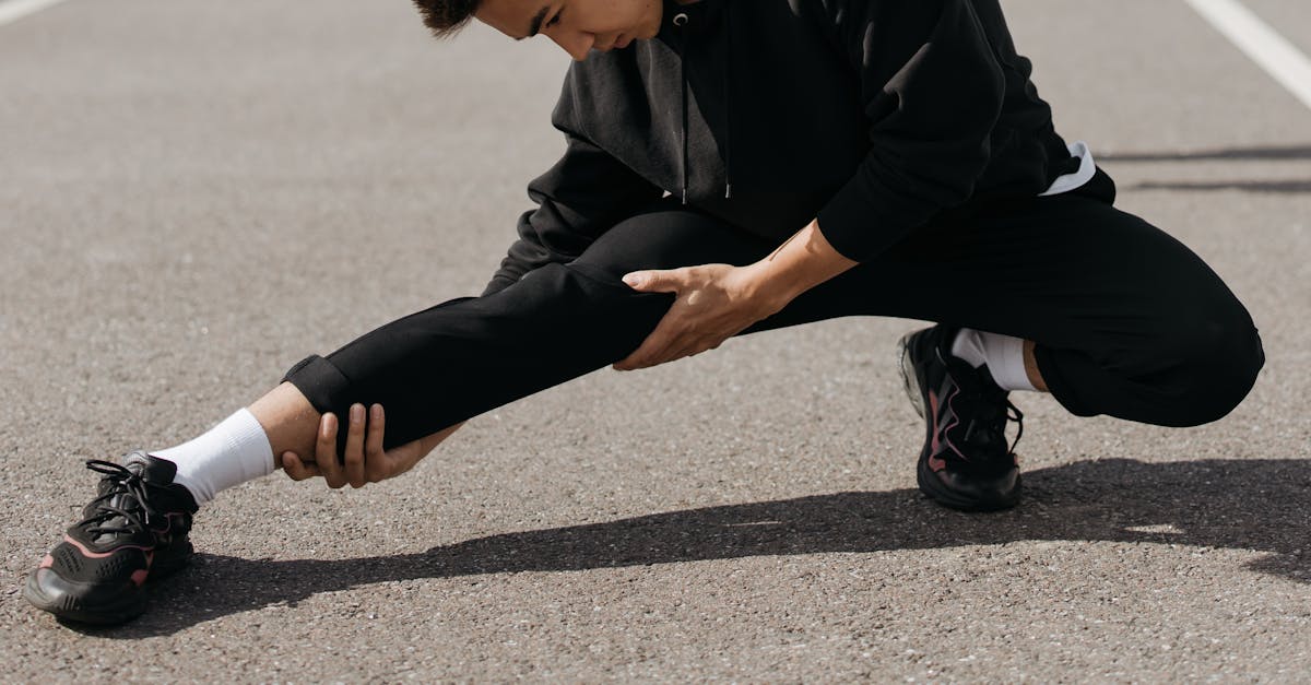 A young man performs stretching exercises on a city street, focusing on flexibility and fitness.