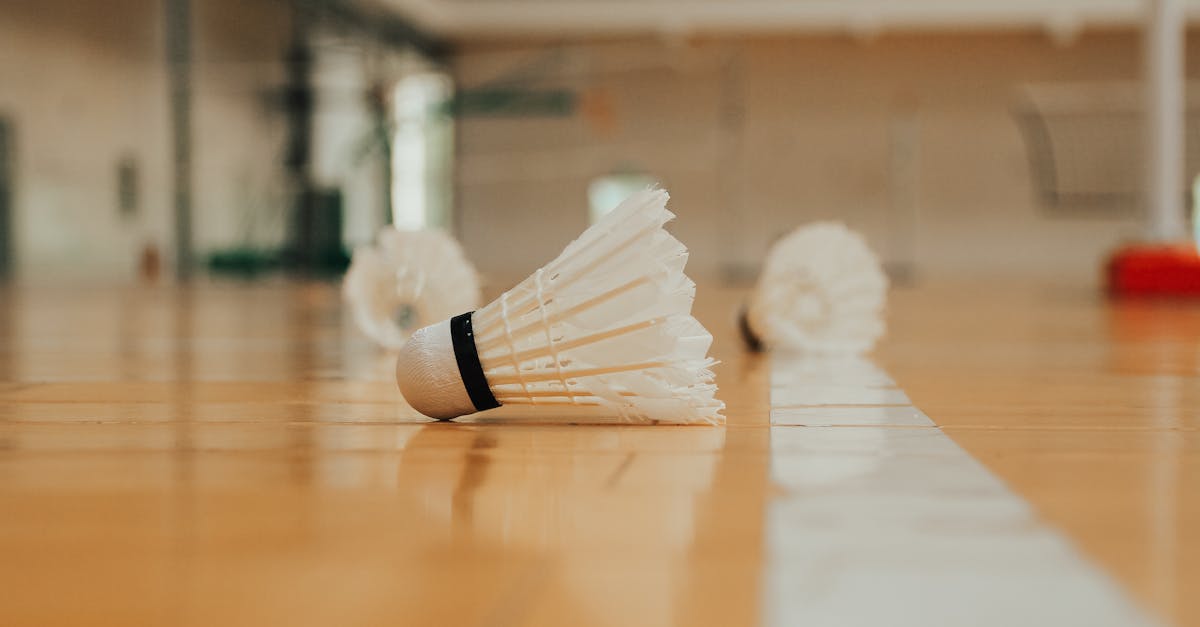 Ground level of similar plastic shuttlecocks reflecting on bright shiny floor with marking line