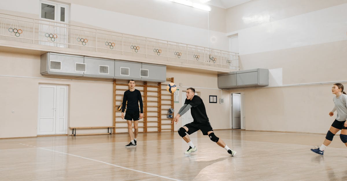 Team of athletes playing volleyball in an indoor court during a casual match.