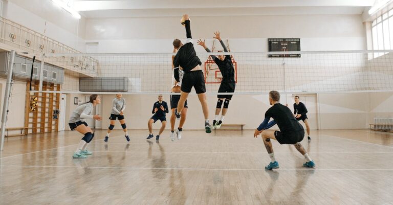 Men and women engaged in a competitive indoor volleyball match, showcasing teamwork and athleticism.