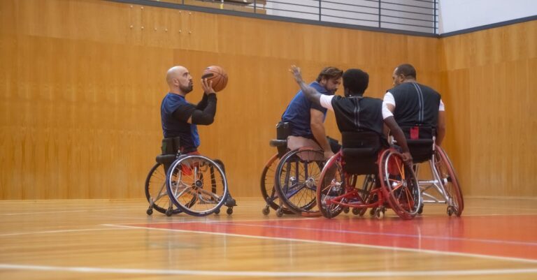 A group of athletes playing wheelchair basketball indoors on a wooden court.