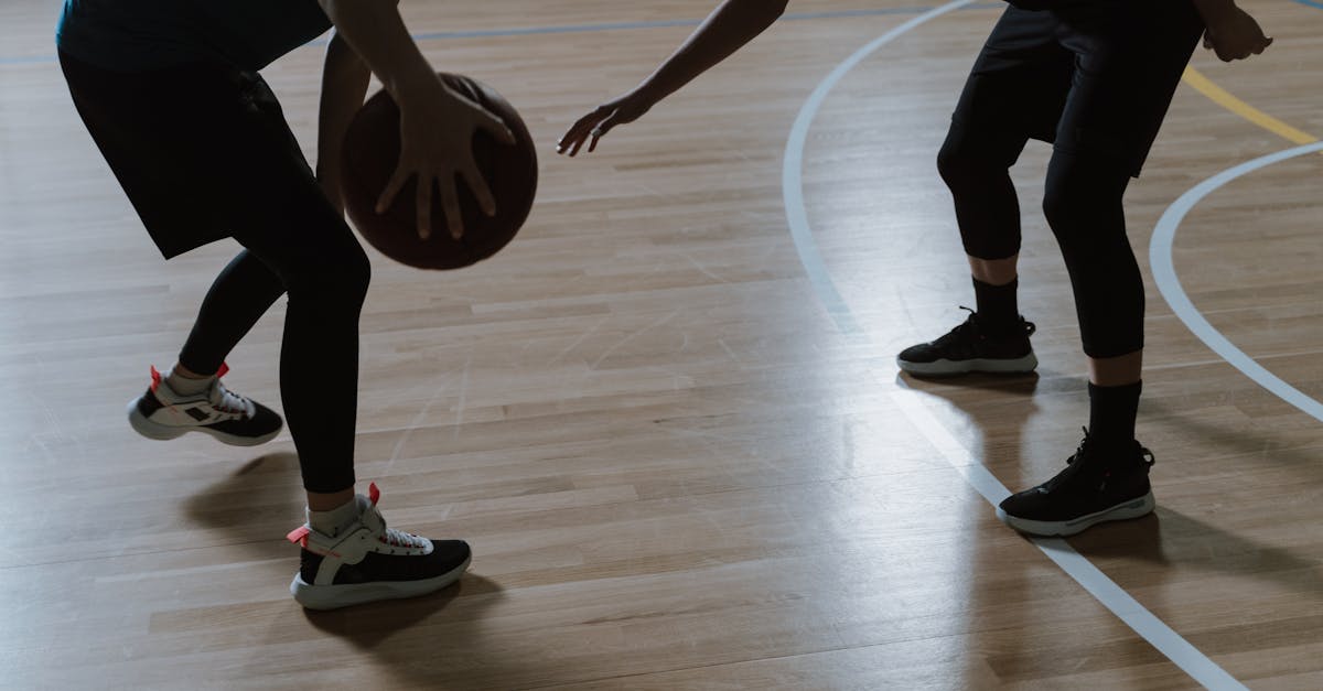 Silhouette of two players engaged in a basketball match on an indoor court.