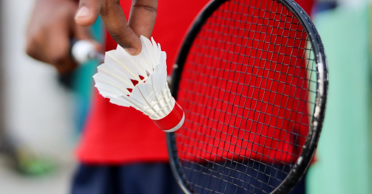 A detailed view of a hand holding a badminton shuttlecock and racket, ready to play.