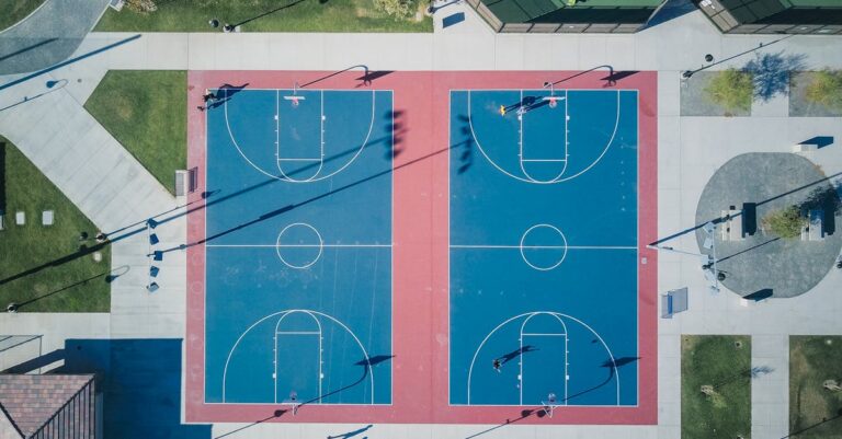 A stunning aerial view of two outdoor basketball courts showcasing vibrant blue and red colors.