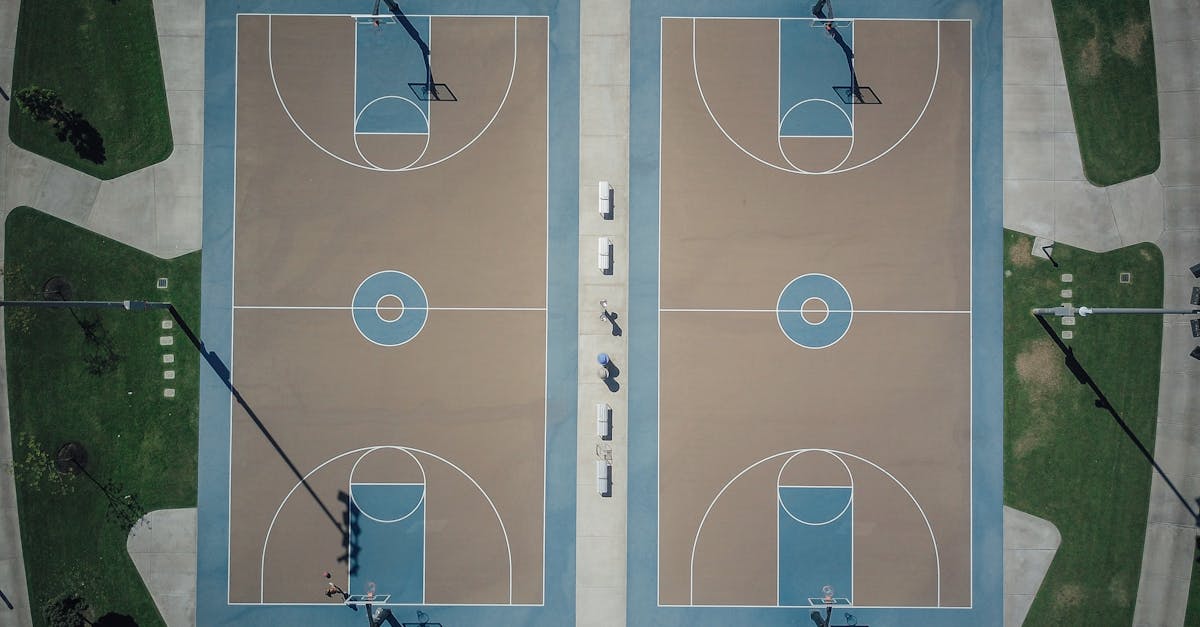 Drone shot of twin outdoor basketball courts surrounded by greenery.