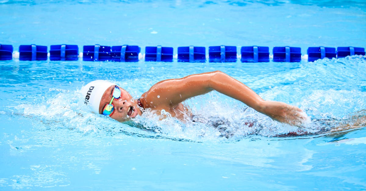 A swimmer energetically performs a freestyle stroke in a clear outdoor swimming pool, showcasing competitive spirit.