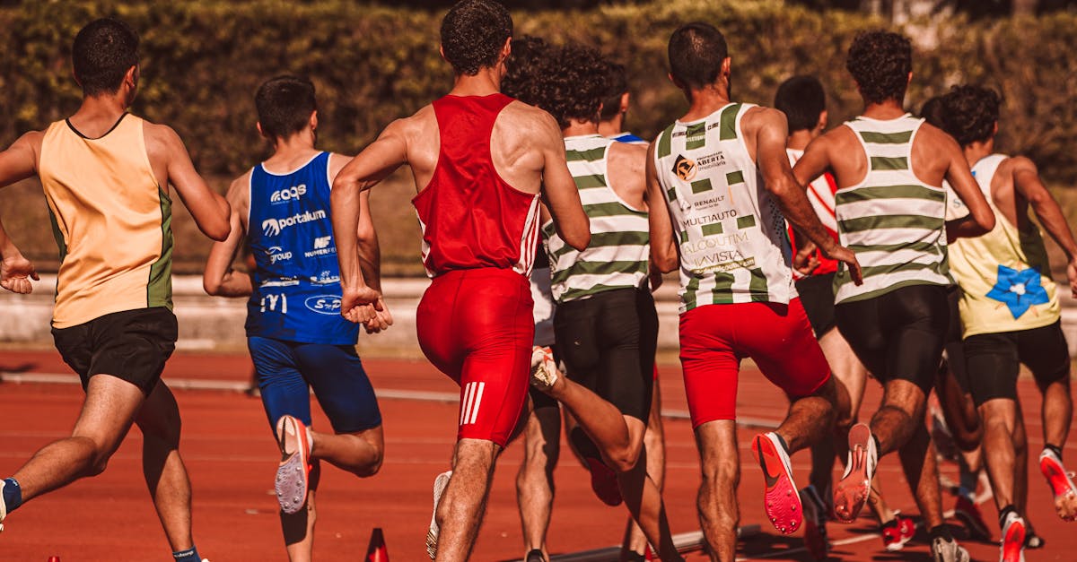 A group of male athletes competing in a track and field event outdoors under a sunny sky.