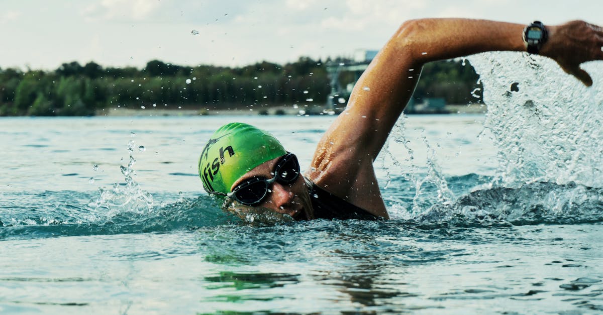 A male swimmer in a green cap and goggles competing in an open water race.