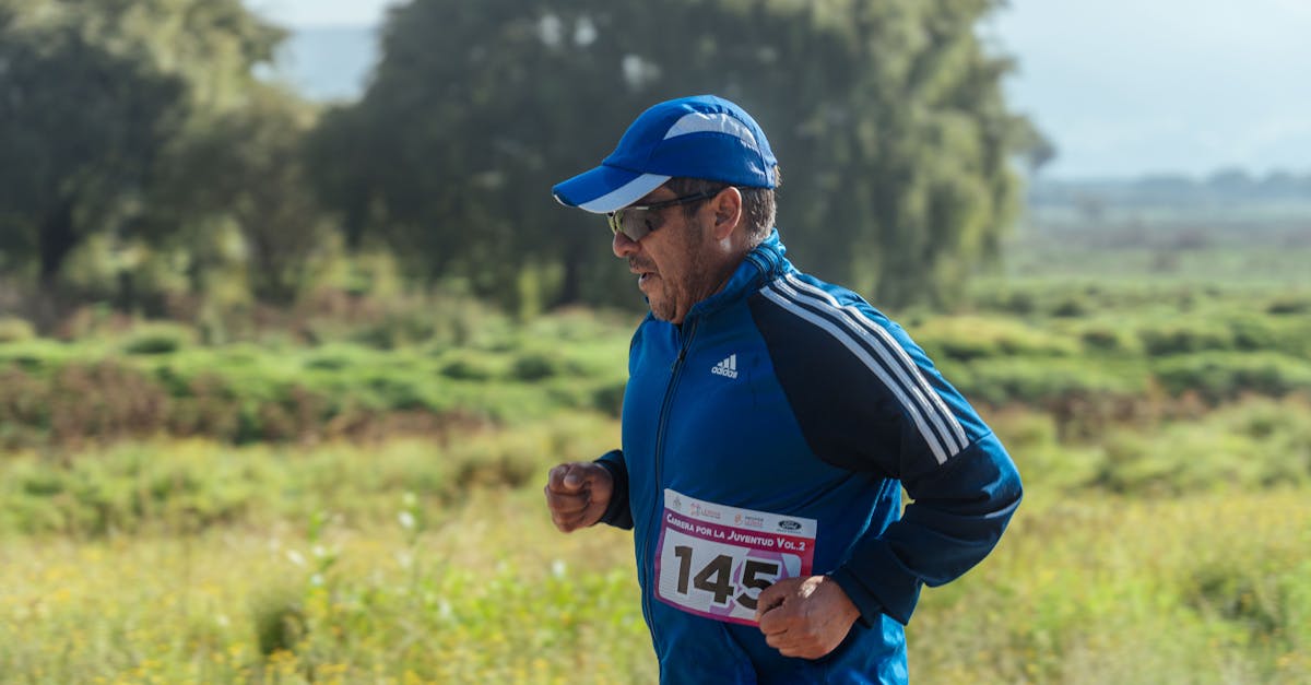 Middle-aged man in athletic gear jogging outdoors during a marathon race on a sunny day.