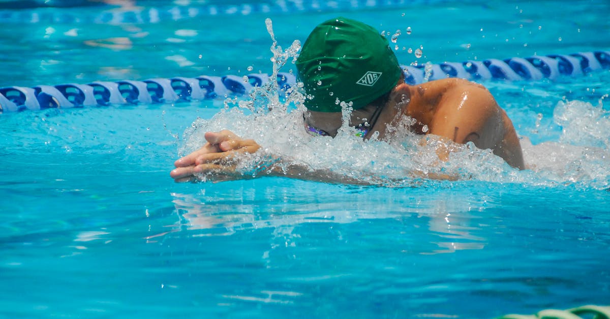 Focused swimmer in a pool during a race, featuring dynamic water splashes and vibrant turquoise water.