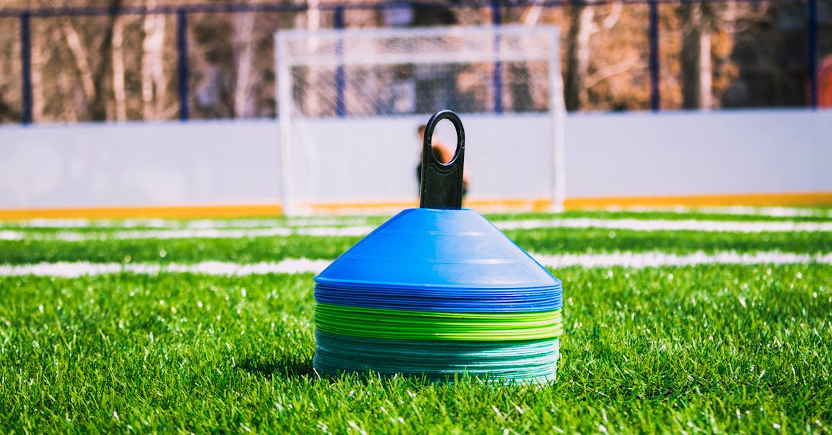 Colorful training cones on an outdoor soccer field with goal in the background.