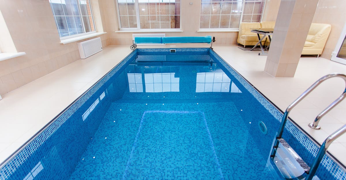 Bright indoor swimming pool with luxury seating and large windows.