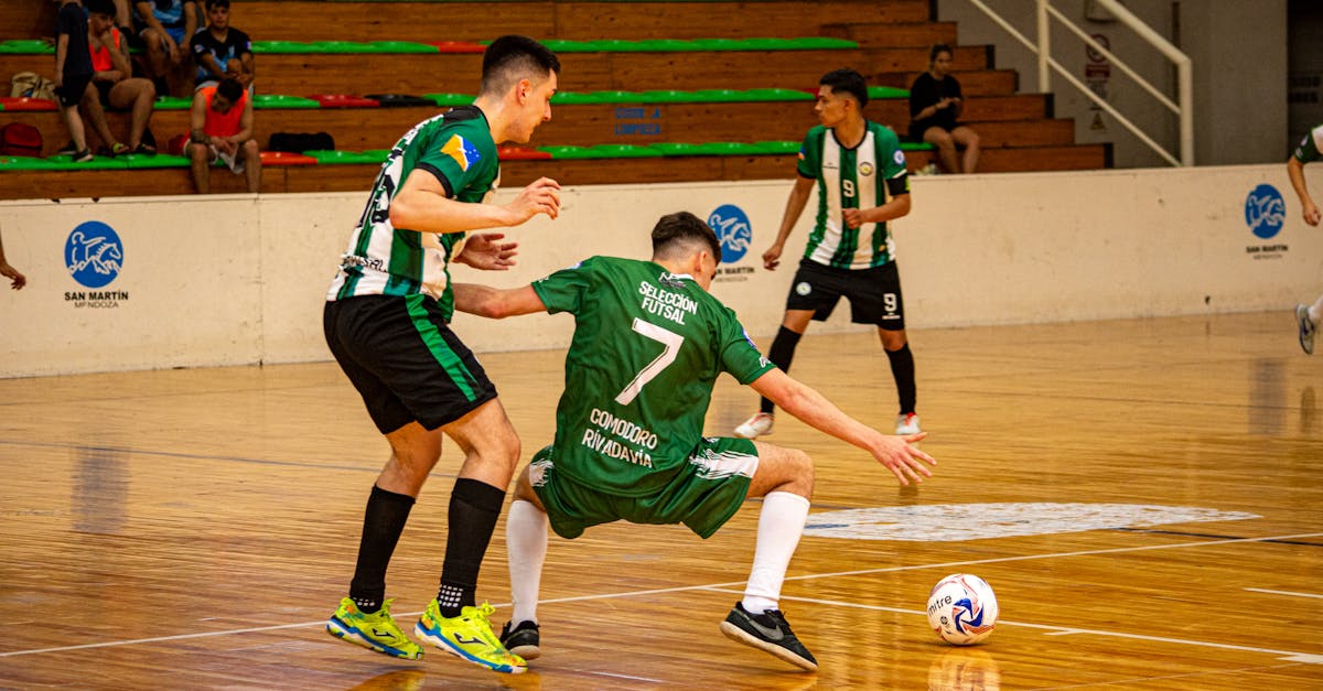 Exciting indoor futsal match with athletes competing on a polished wooden court. permainan futsal