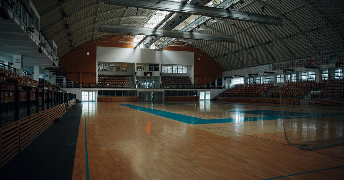 Empty indoor sports arena with hardwood flooring and bleachers, perfect for various sports activities. ukuran lapangan futsal, gambar lapangan futsal