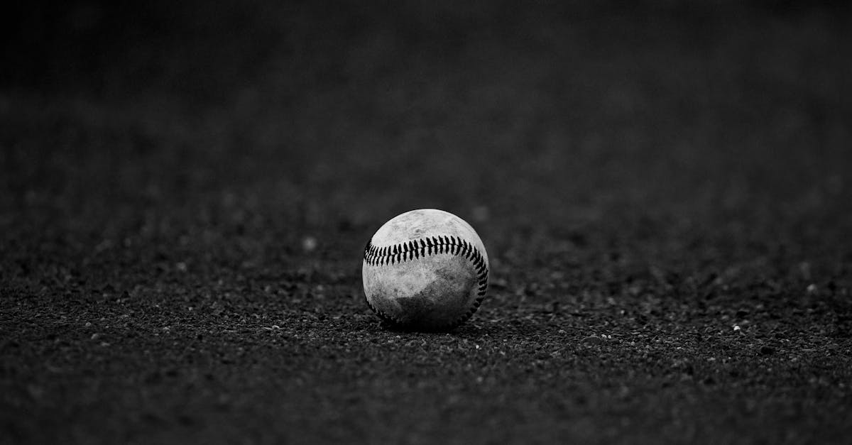 A monochrome image of a baseball resting on a textured dark surface, perfect for sports themes.