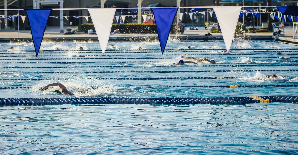 Swimmers competing in an outdoor pool under blue and white banners on a sunny day.