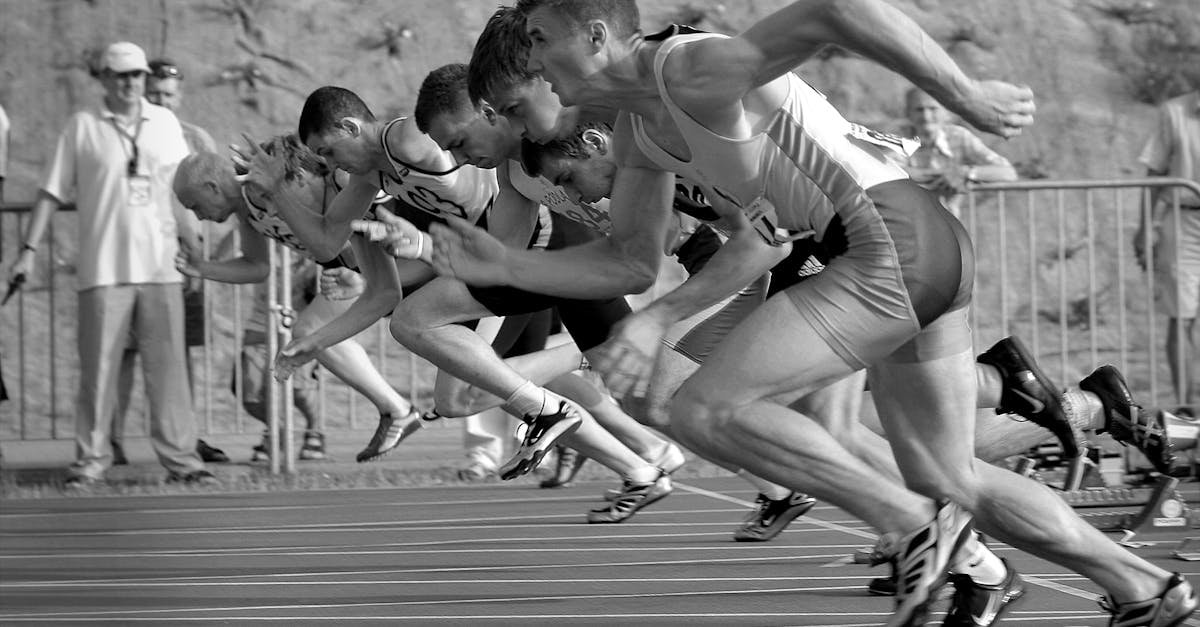 Athletes burst from the blocks during a sprint race, captured in monochrome.